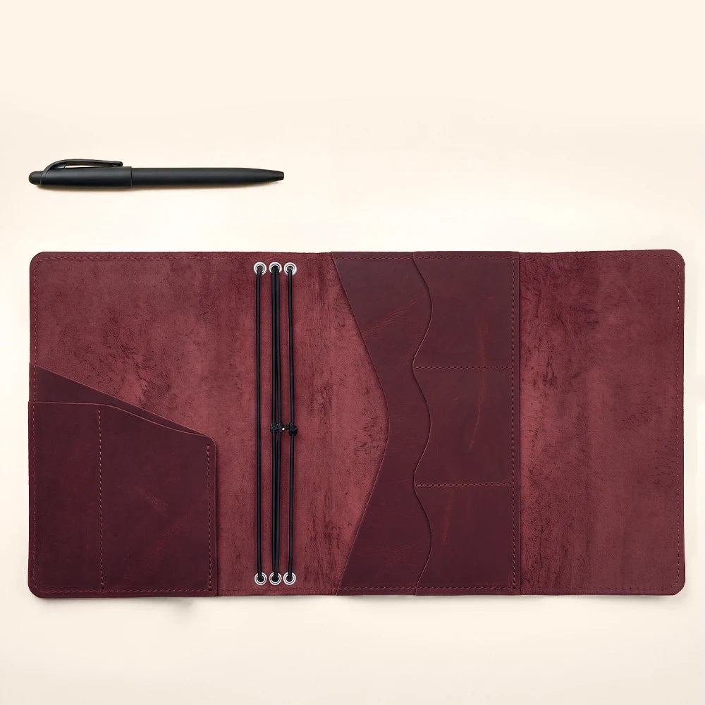 Handmade leather notebook organizer designed with secure elastic inserts and pen storage loop.