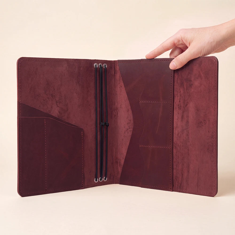 Handmade leather notebook wrap providing secure elastic insert placement and pen storage solution.
