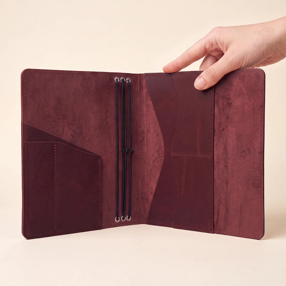 Durable leather journal cover with three elastic bands for multiple notebook inserts.