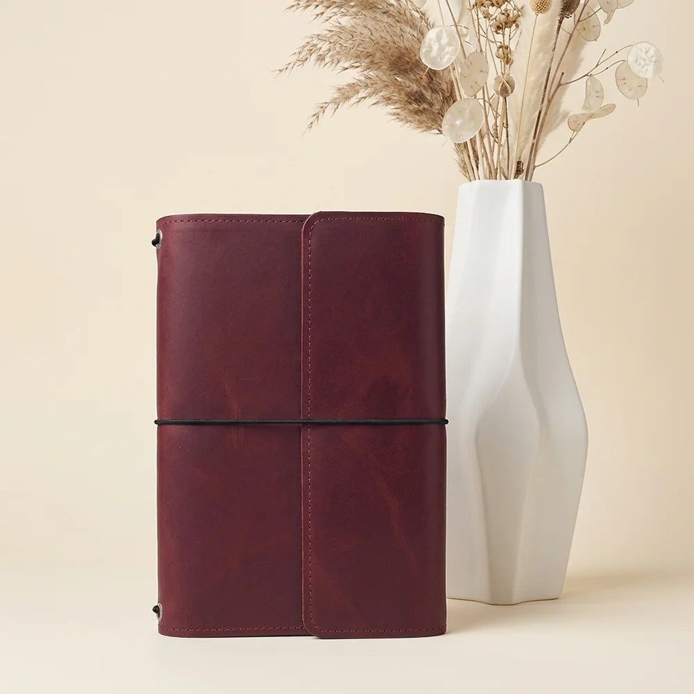 Textured leather journal cover with several internal slots and an integrated pen keeper.
