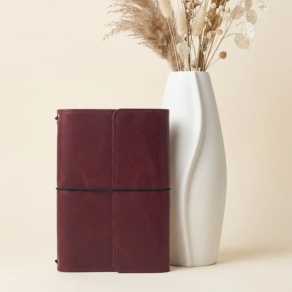 Natural leather notebook organizer displaying interior slots and a convenient loop for carrying pens.