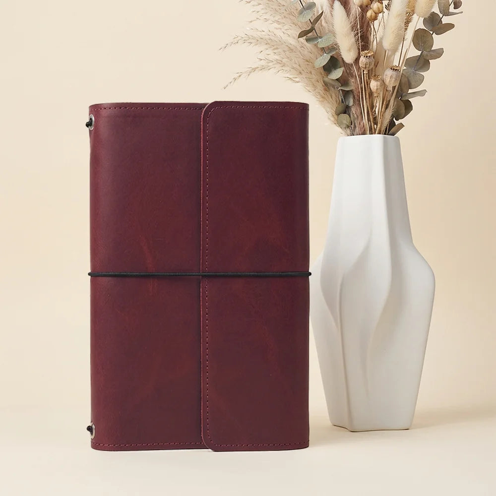 Natural leather journal holder with multiple stitched compartments and a practical pen retaining loop.