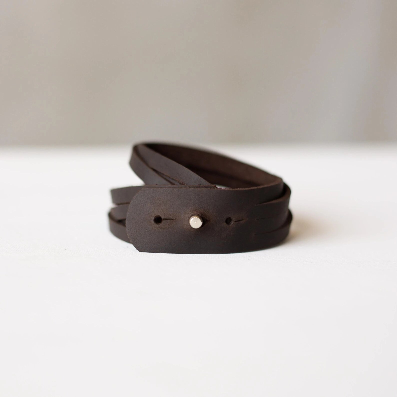 Brown leather belt on a white surface with a light gray background