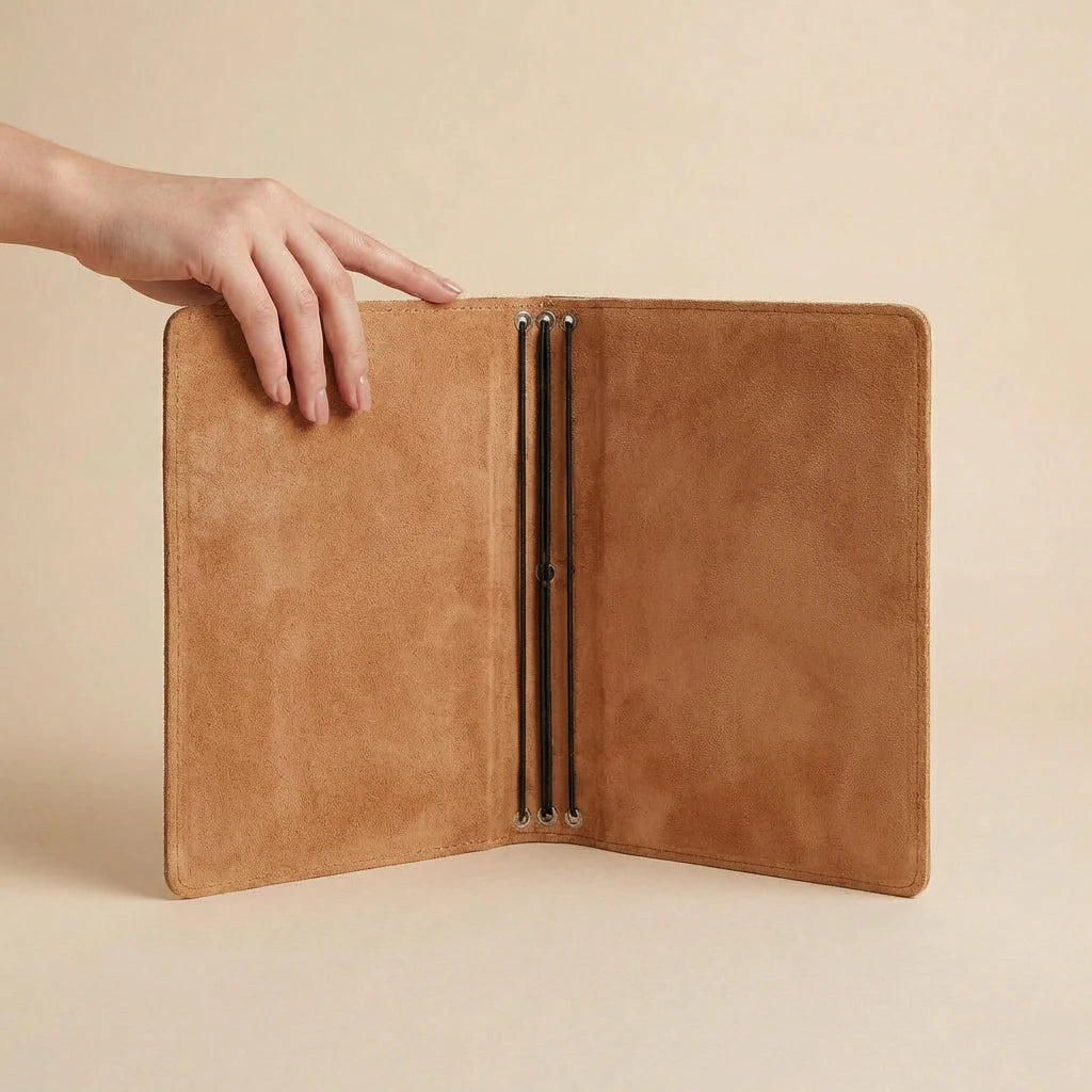 Brown leather journal cover held open by a hand on a beige background