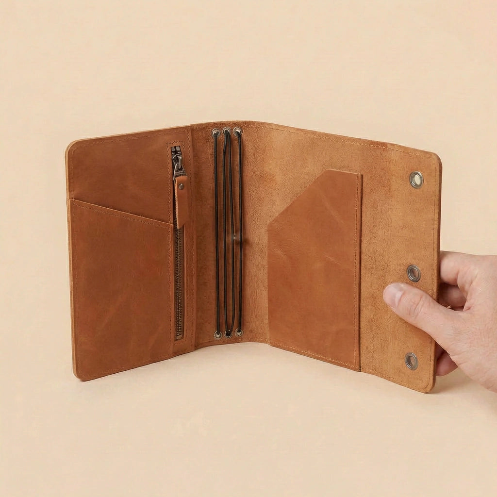 Brown leather journal cover held open by a hand on a beige background