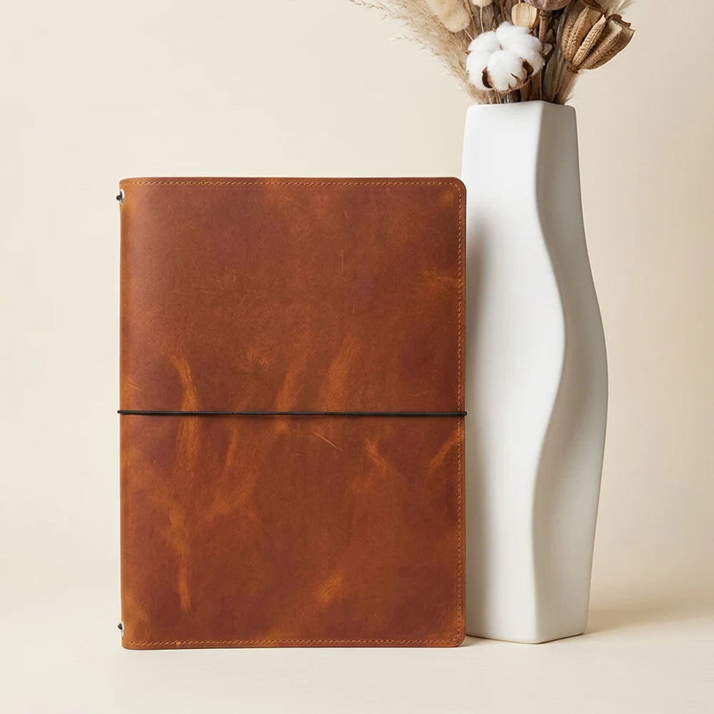 Refillable leather journal holder with three elastic attachment points for notebook refills.