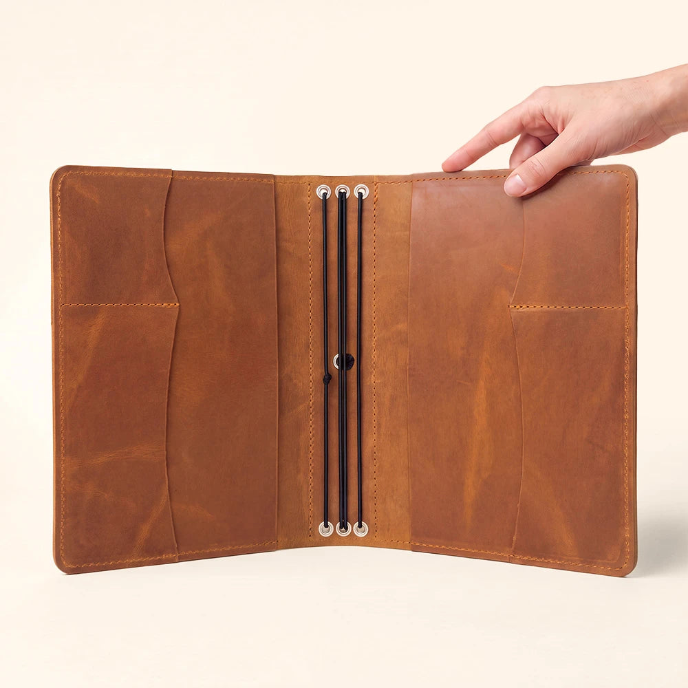 Premium leather notebook holder with interior compartments and integrated writing instrument loop.