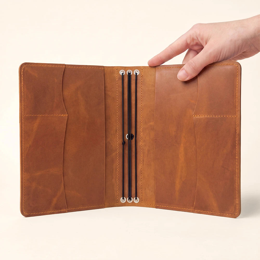 Refillable leather notebook organizer with storage pockets and secure pen loop inside cover.