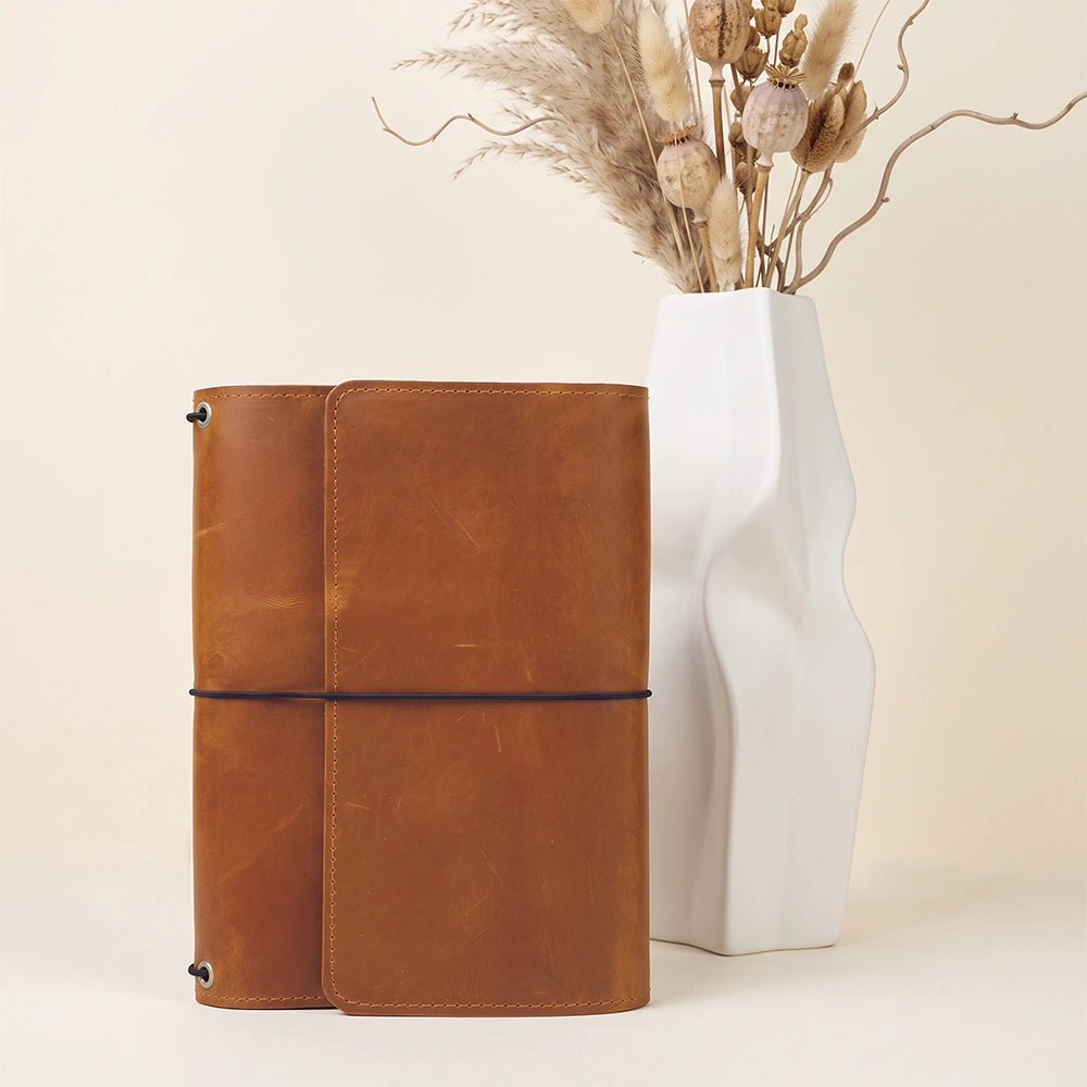 Rustic handcrafted leather notebook organizer with organized compartments and integrated pen holder.