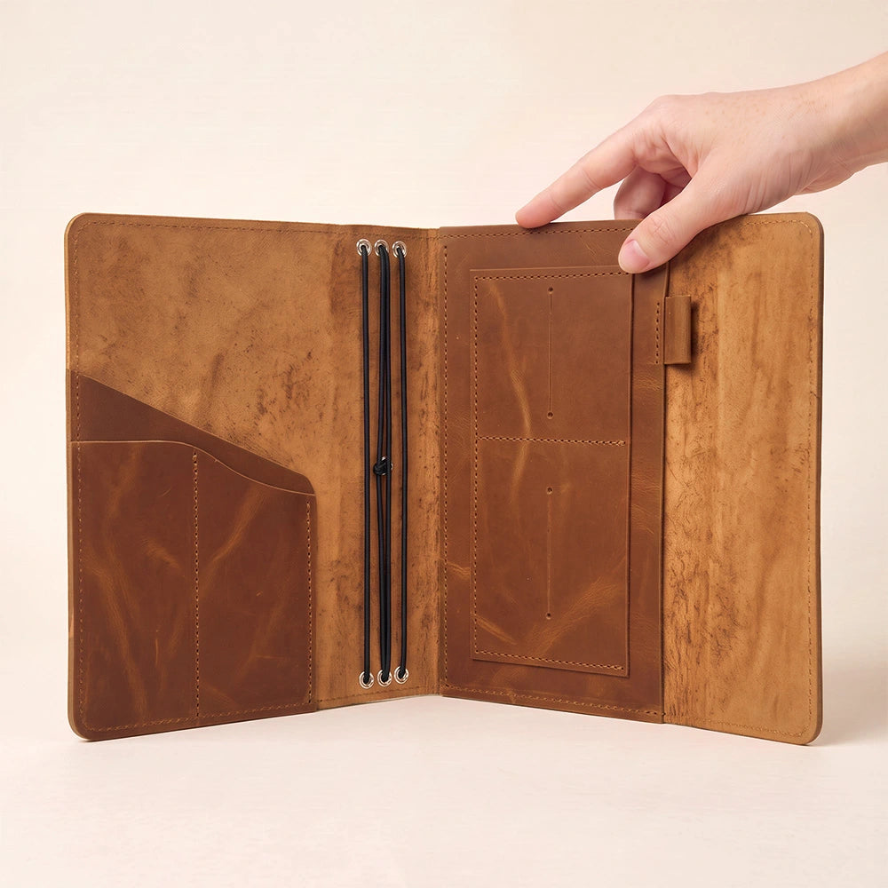 Refillable leather notebook wallet with inside organizer and secure pen retaining strap.