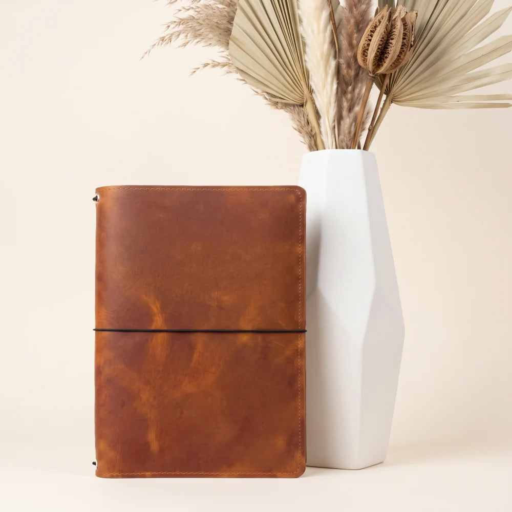 Natural leather journal holder with three stretch bands for personalized notebook organization.