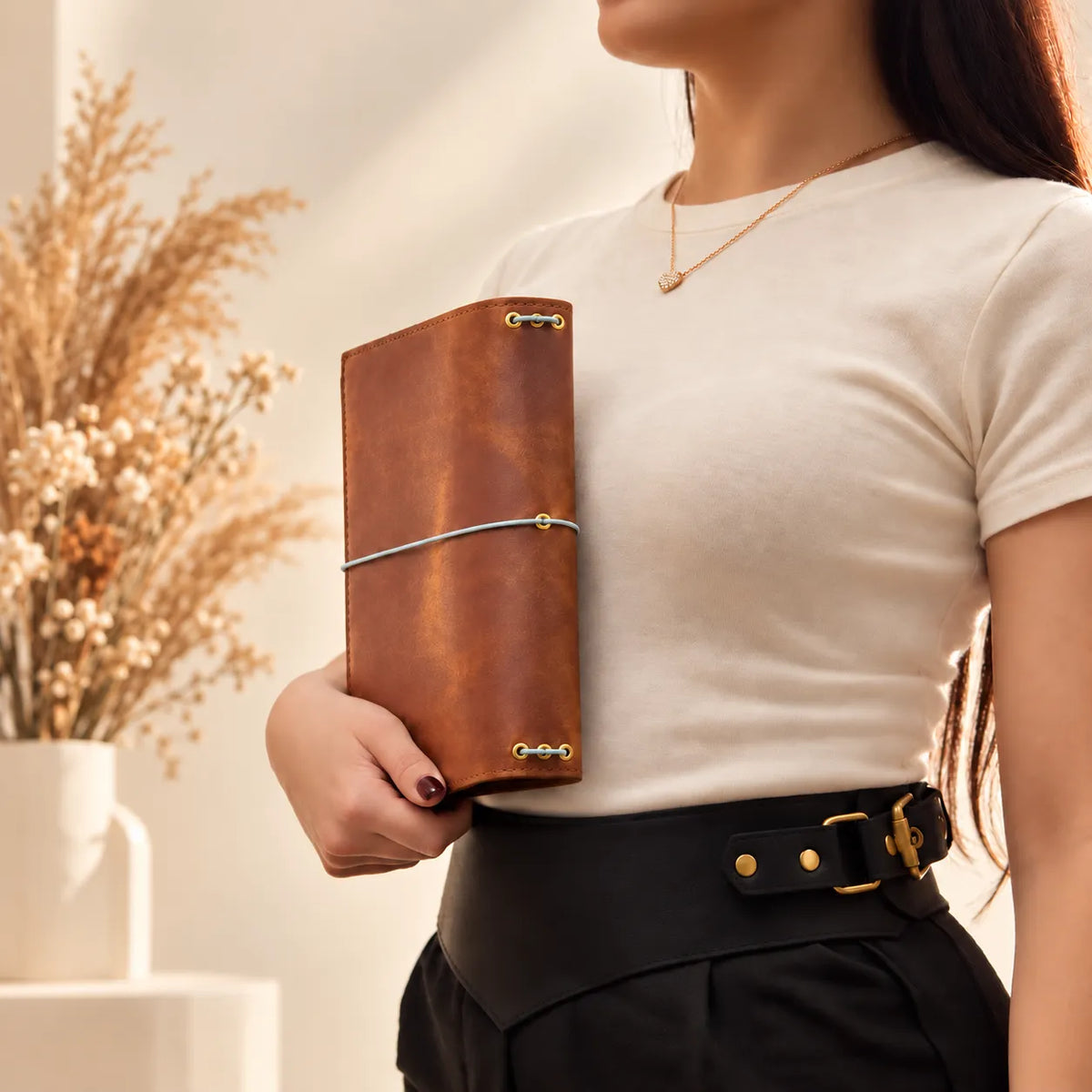 Female hands presenting a genuine leather journal cover, emphasizing its authentic grain and craftsmanship.