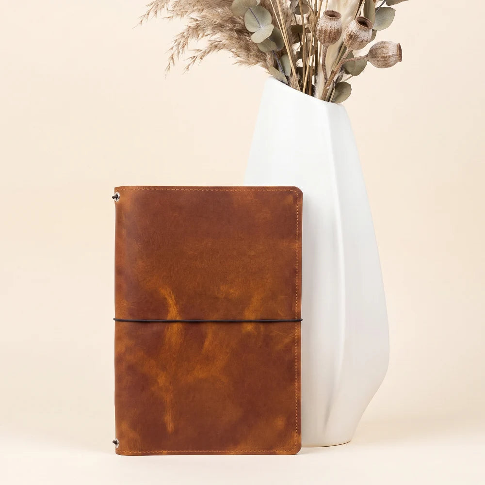 Refillable natural leather travel journal with three secure elastic holders inside.