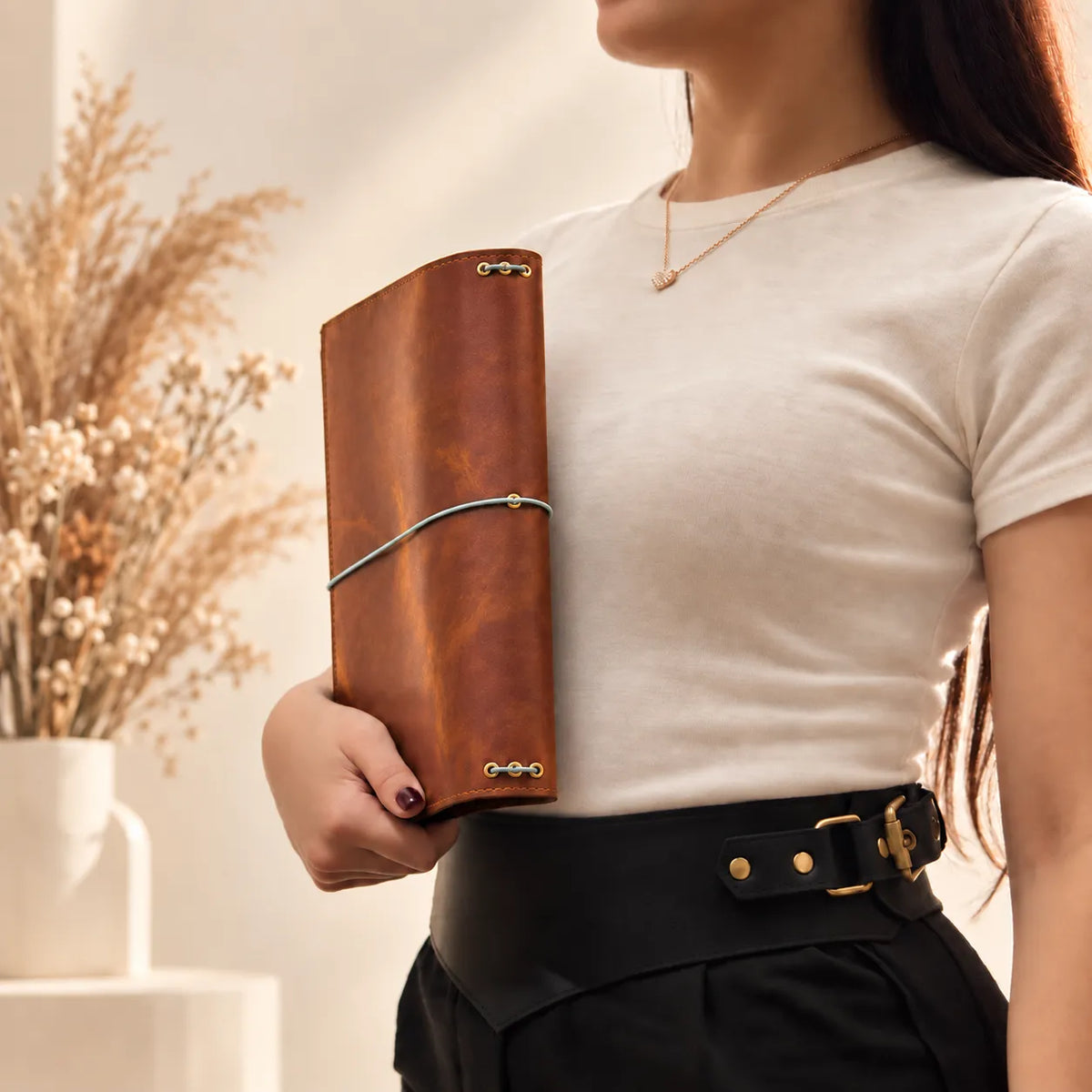 Woman holding a leather notebook cover made from natural leather with visible handcrafted details.