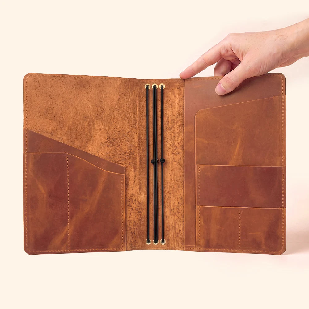 Natural leather planner cover designed to hold three refillable notebook inserts.