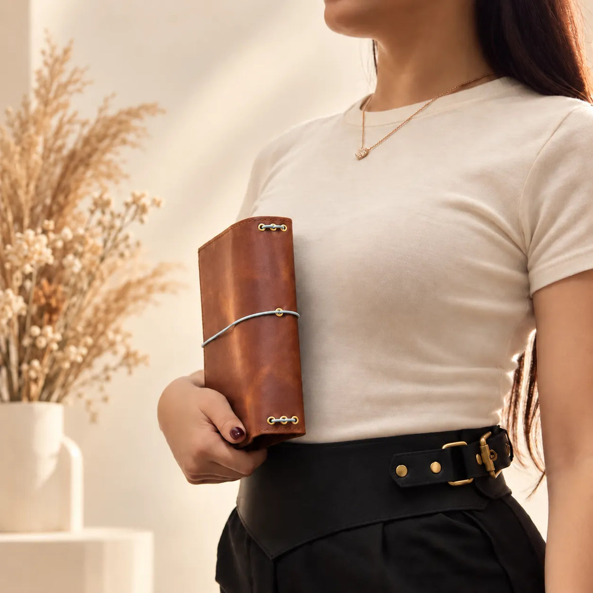 Woman showcasing a genuine leather journal cover with textured surface and carefully finished edges.