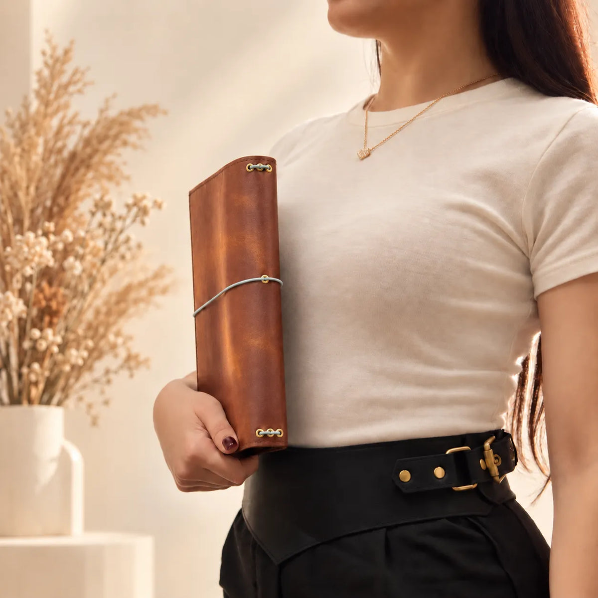 Young woman holding a handmade natural leather notebook cover with an elegant rustic design.