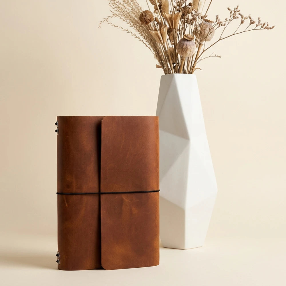 Stylish leather journal cover supporting six inserts with an integrated pen holder.
