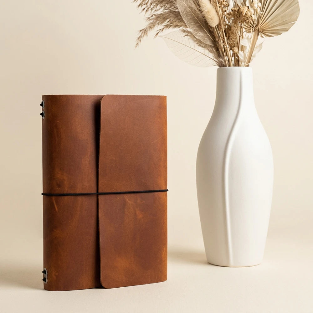 Minimalist refillable journal case with six elastic straps and integrated pen holder.