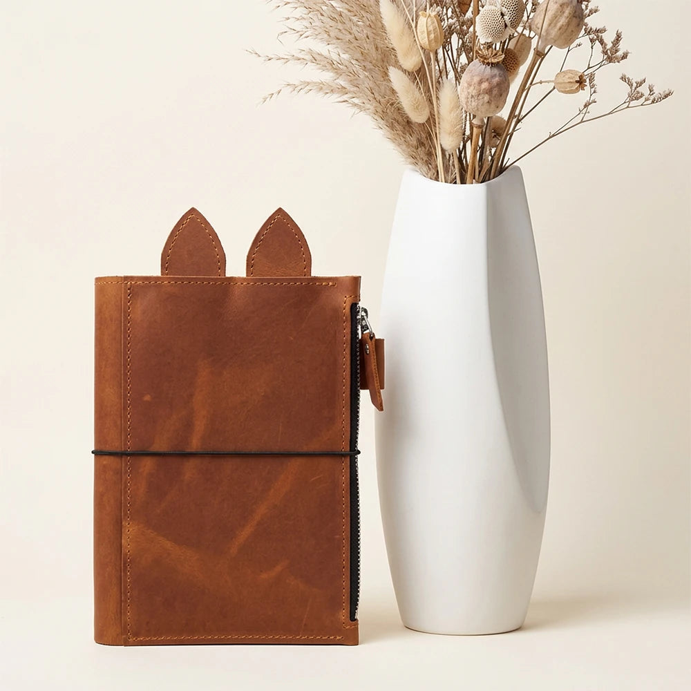 Genuine leather writing cover featuring an integrated zipper compartment and pen loop.