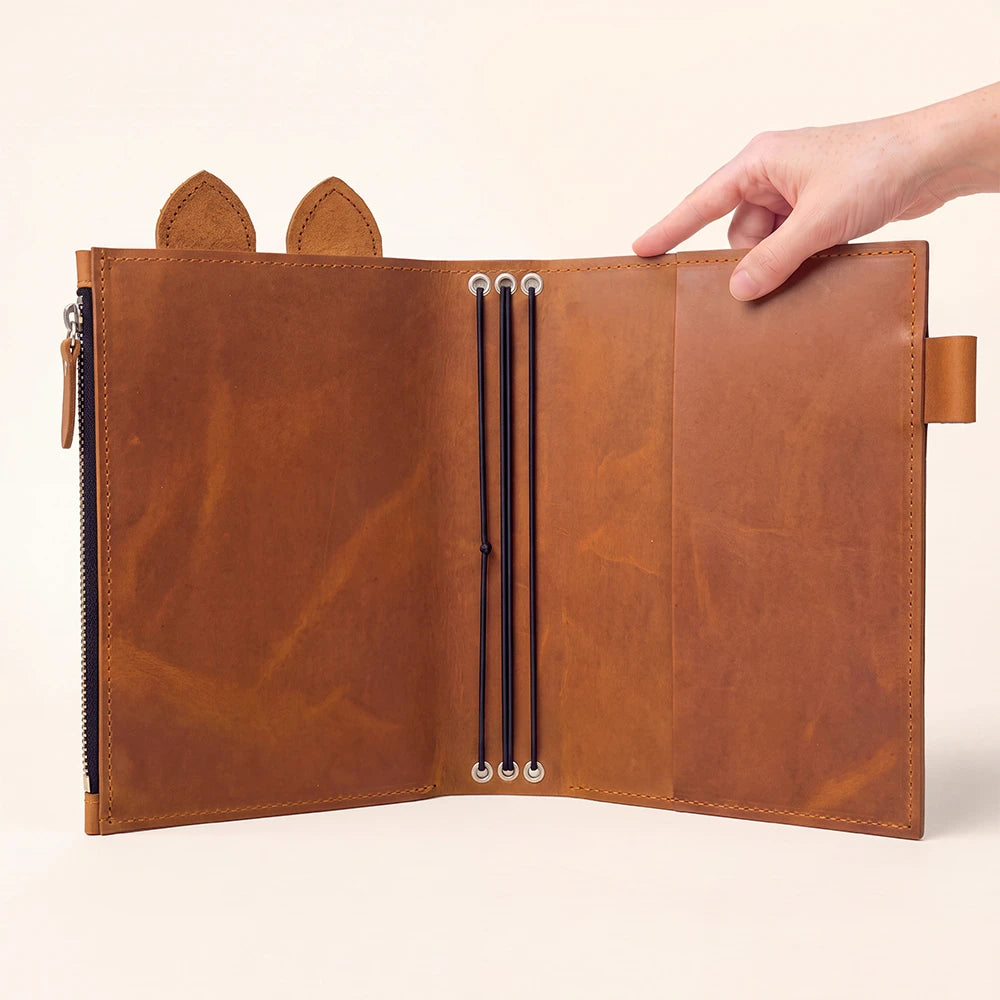 Open brown notebook organizer showcasing decorative tabs and handcrafted leather texture