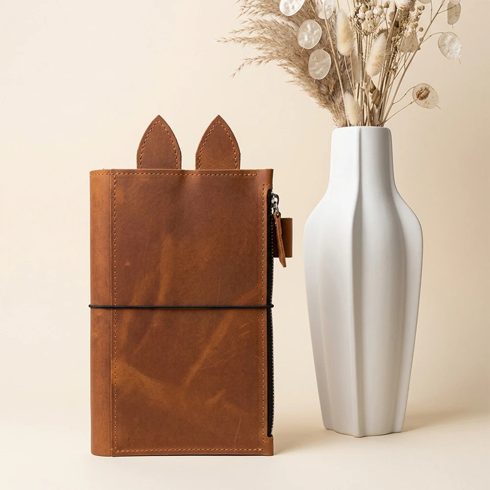 Handmade leather notebook case with decorative tabs and convenient zippered storage.