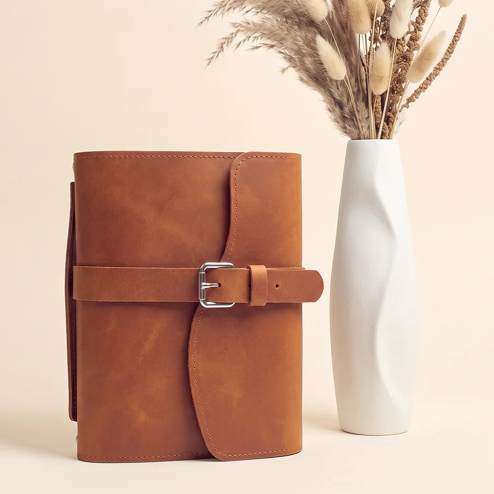 Genuine hide notebook sleeve displaying useful pockets, pen loop, integrated marker, and convenient exterior handle.