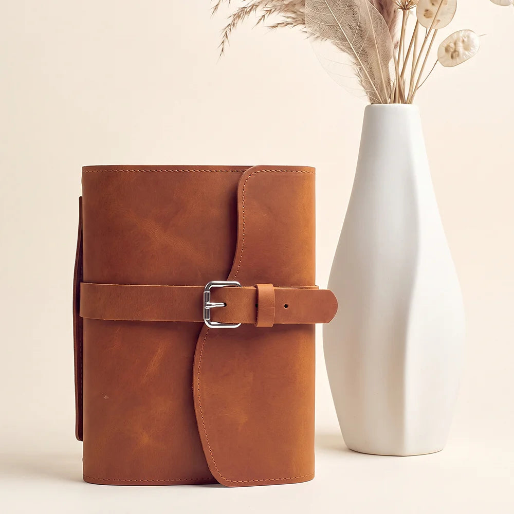 Natural leather notebook sleeve with practical storage pockets, pen loop, integrated bookmark, and carry grip.