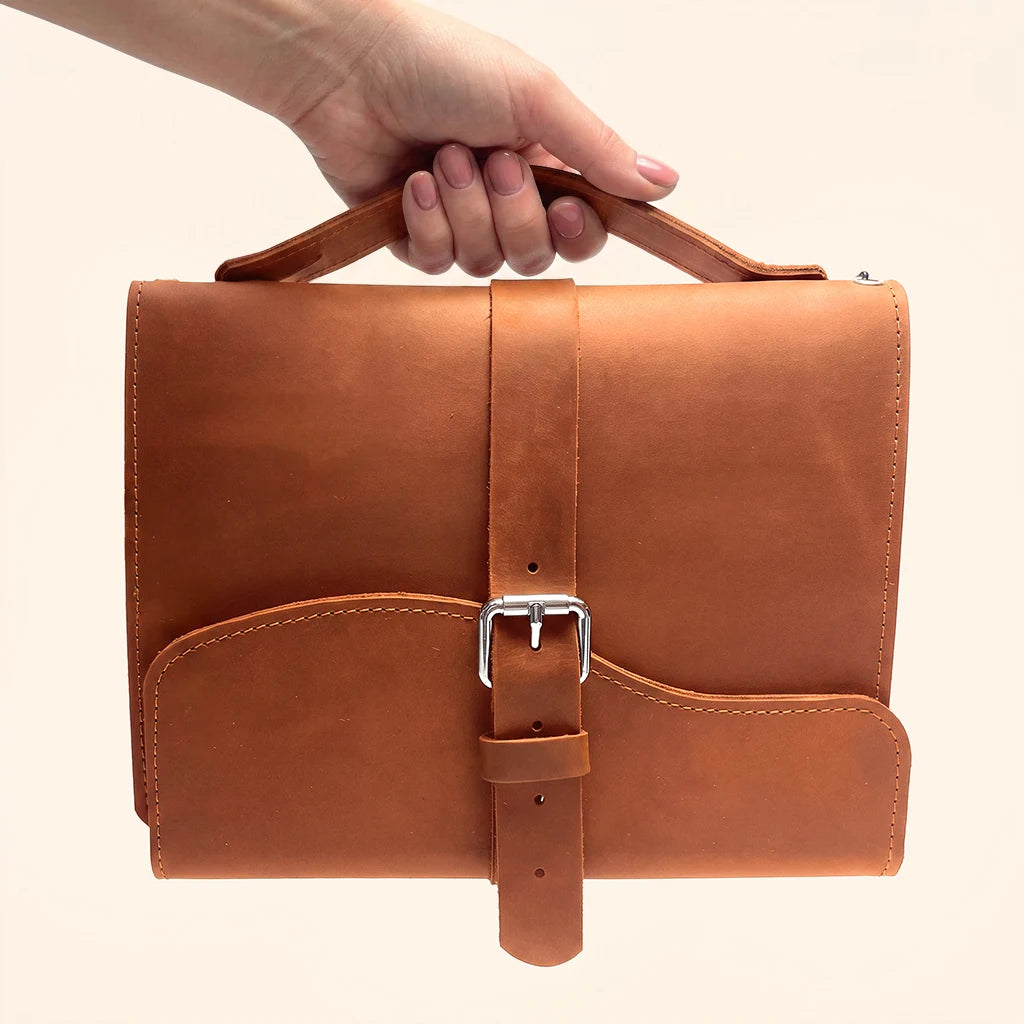 Leather notebook cover designed for three inserts with an external handle for carrying.