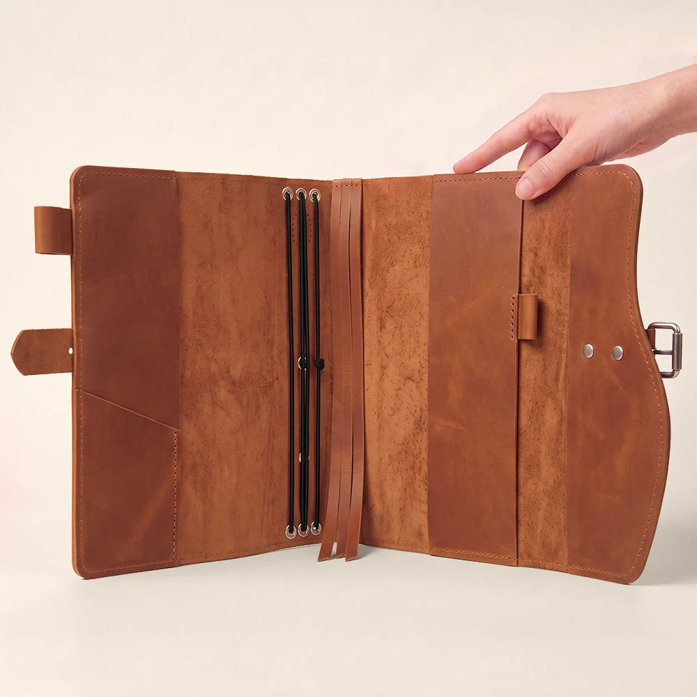 Genuine leather notebook organizer showcasing several pockets, pen loop, ribbon bookmark, and sturdy leather grip.