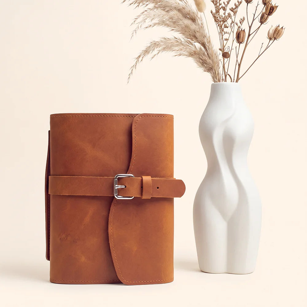 Genuine leather planner cover displaying inner storage sections, elastic pen loop, ribbon marker, and functional outer handle.