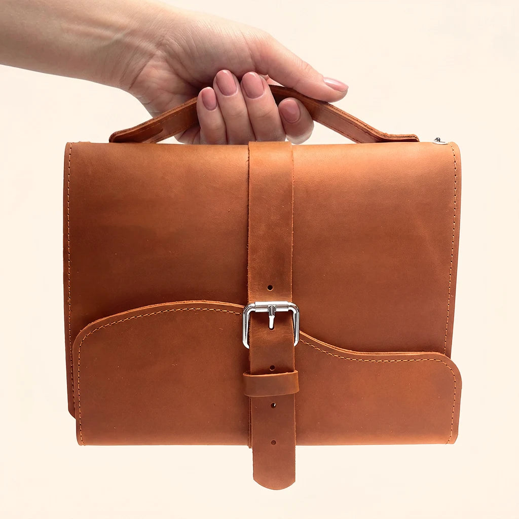 Handmade leather journal cover featuring three elastic loops and an exterior carry handle.