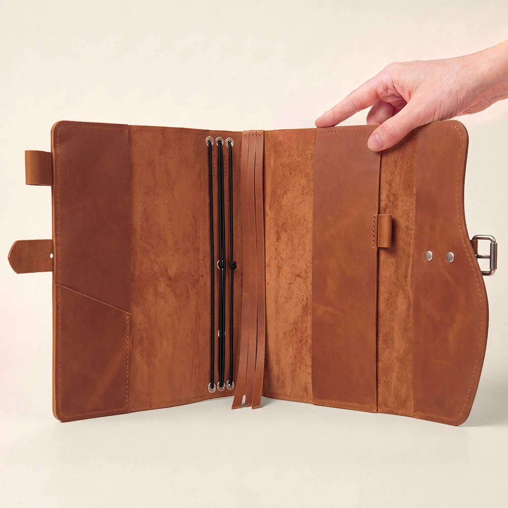 Natural leather journal sleeve displaying useful compartments, pen loop, page marker, and sturdy outside handle.