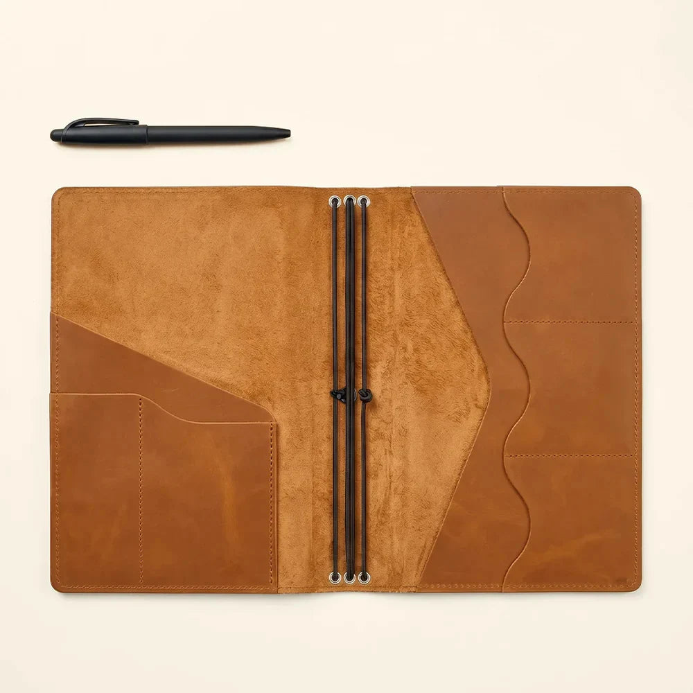 Leather notebook cover with elegant stitching, interior pockets, and notebook retaining elastics.