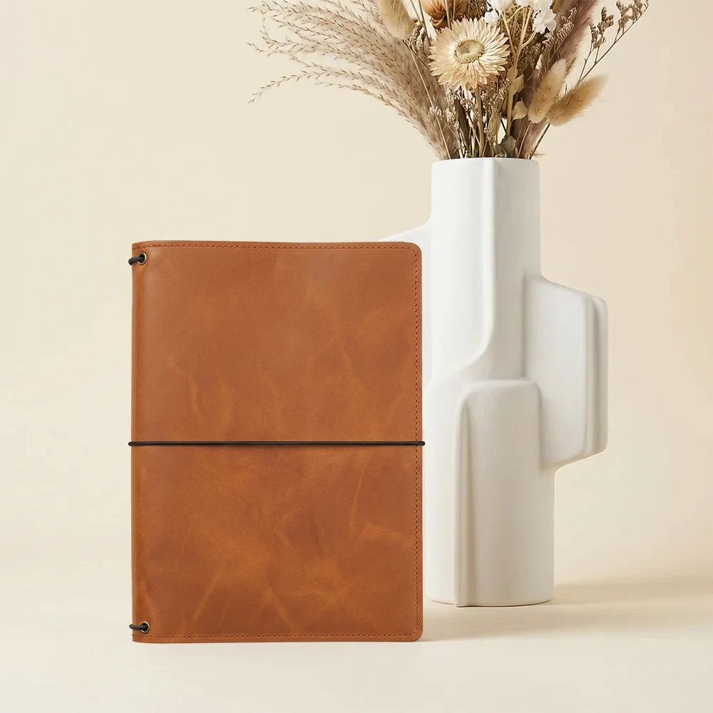 Brown leather journal organizer with multiple pockets and three elastic notebook retaining loops.
