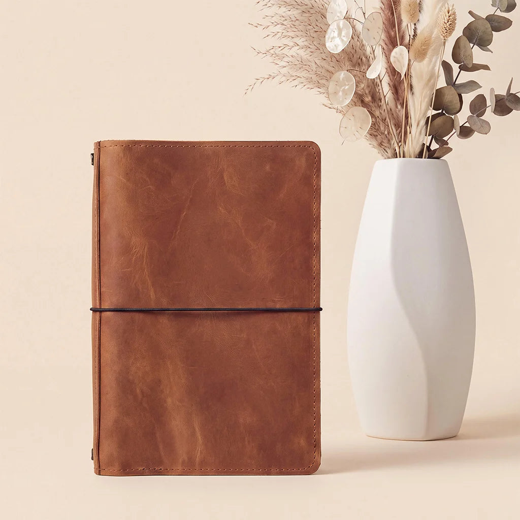 Leather notebook cover designed with refillable insert elastics and organized pocket compartments.
