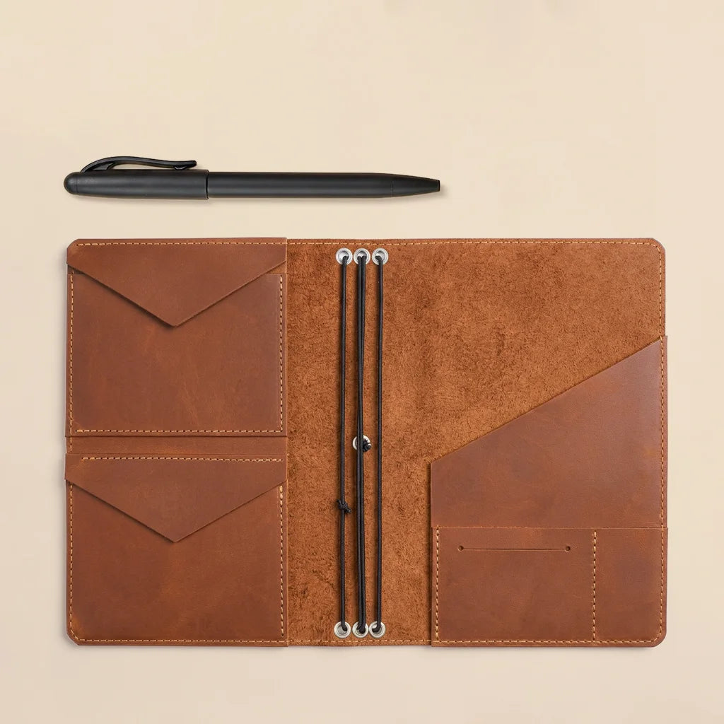 Brown leather notebook cover displaying spacious interior pockets and durable elastic bands.
