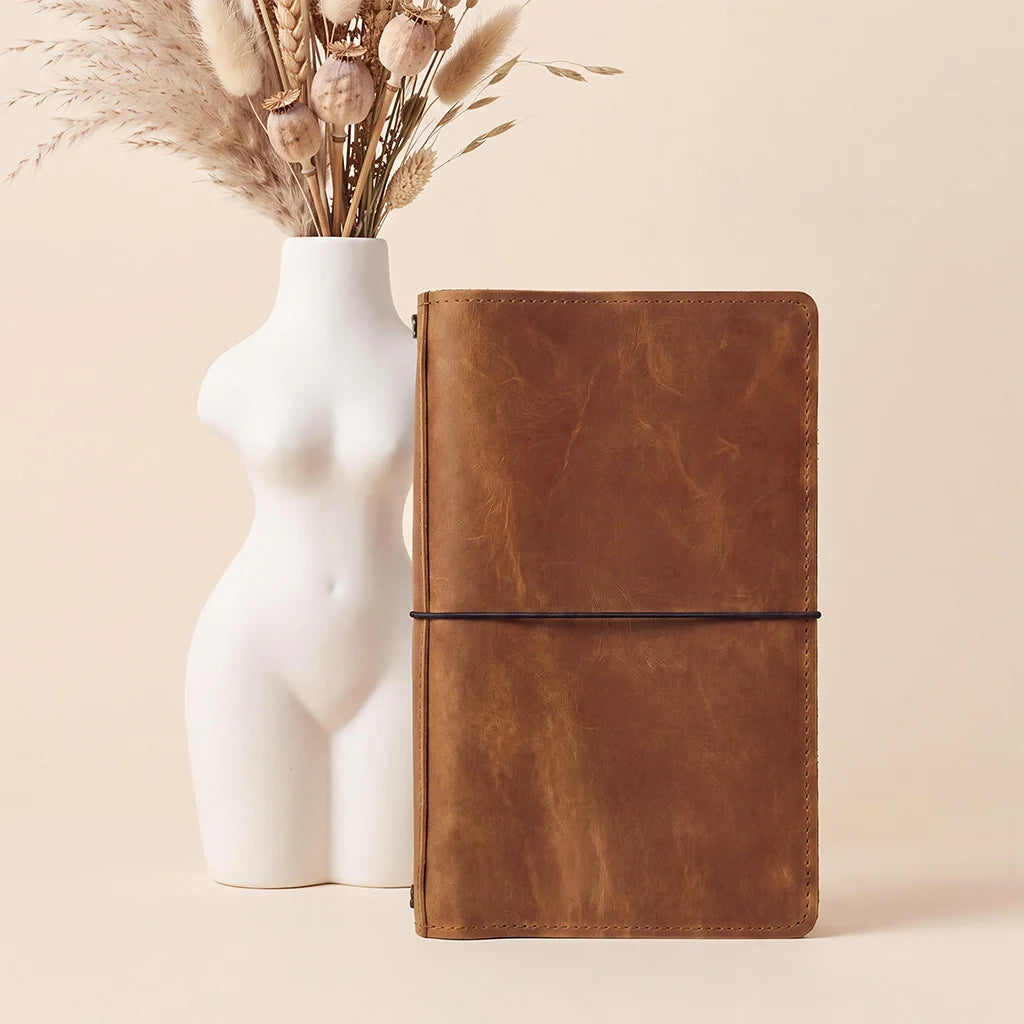 Leather journal cover with flexible elastic notebook holders and spacious storage compartments.