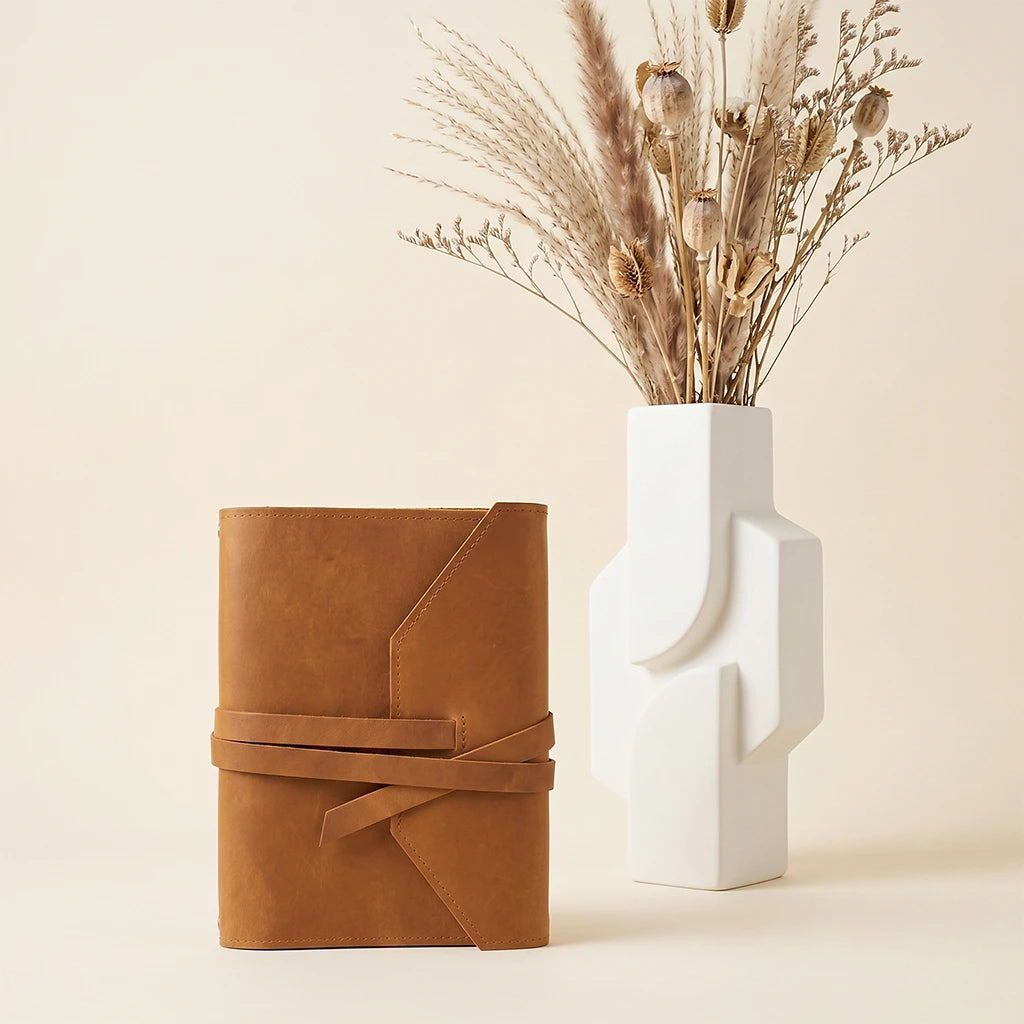 Minimal leather journal holder with secure elastic bands and integrated pen space.