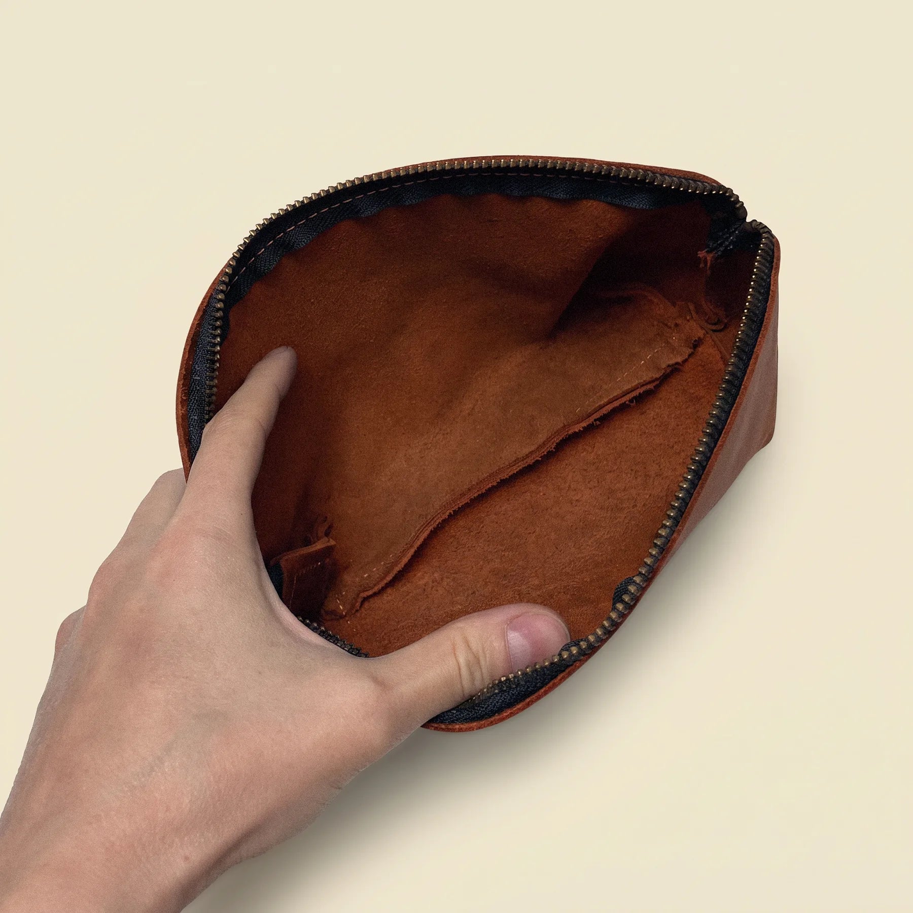 Natural leather makeup pouch featuring a smooth zipper closure and compact design