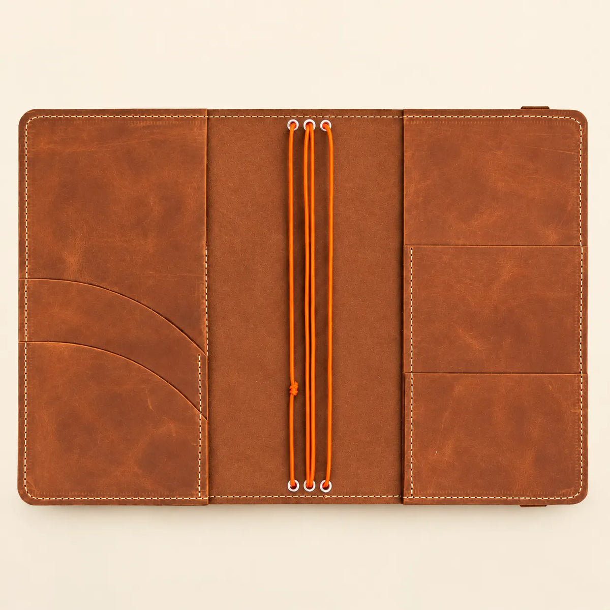 Handmade leather journal cover with three flexible straps and integrated interior storage sections.