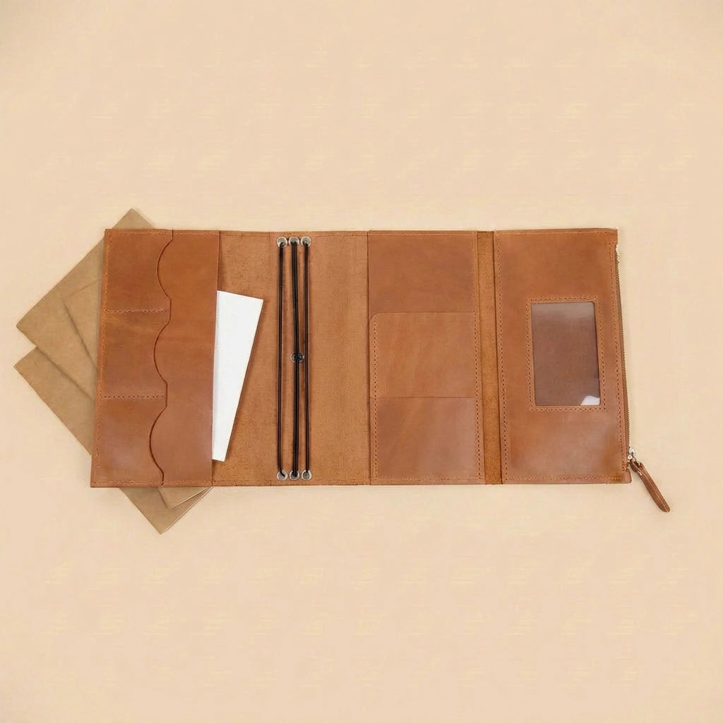 Brown leather journal cover with multiple compartments on a beige background