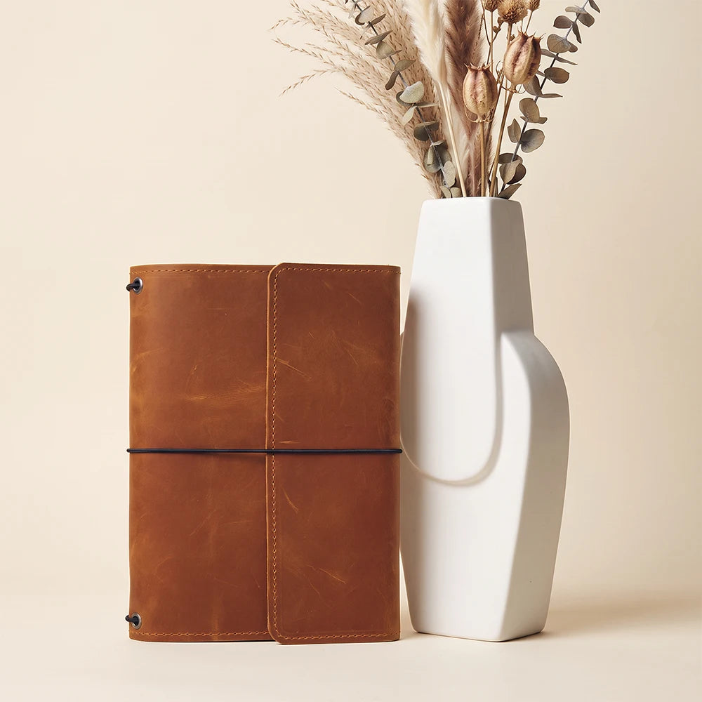 Genuine leather refillable notebook case with practical interior compartments and secure elastic cords.
