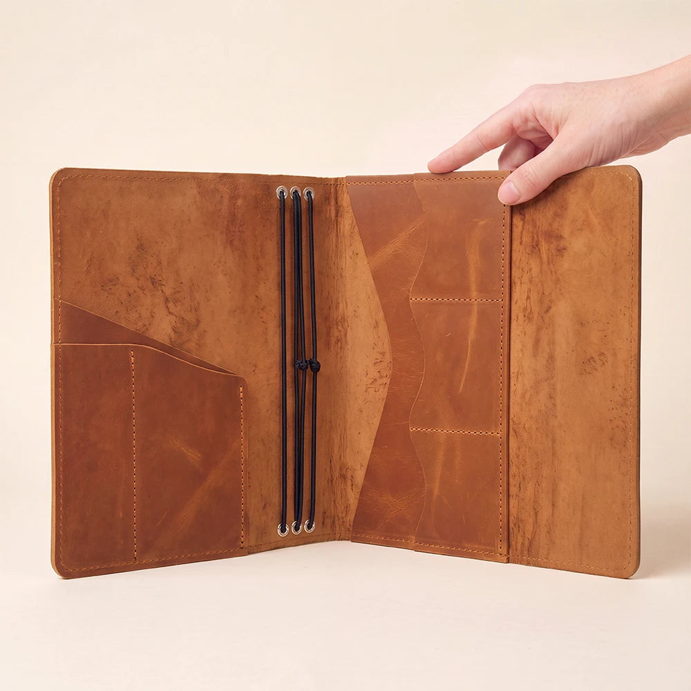 Handmade leather journal portfolio with refillable inserts and functional storage pocket arrangement.