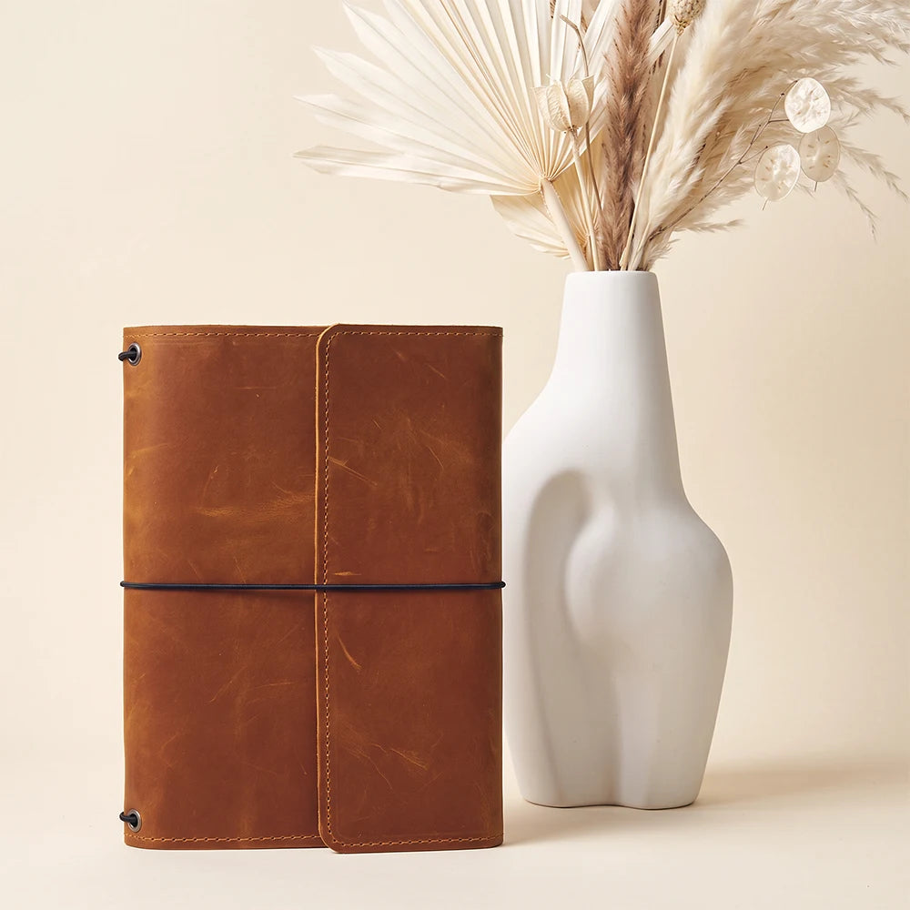 Elegant leather journal organizer featuring three elastic notebook bands and practical interior pockets.