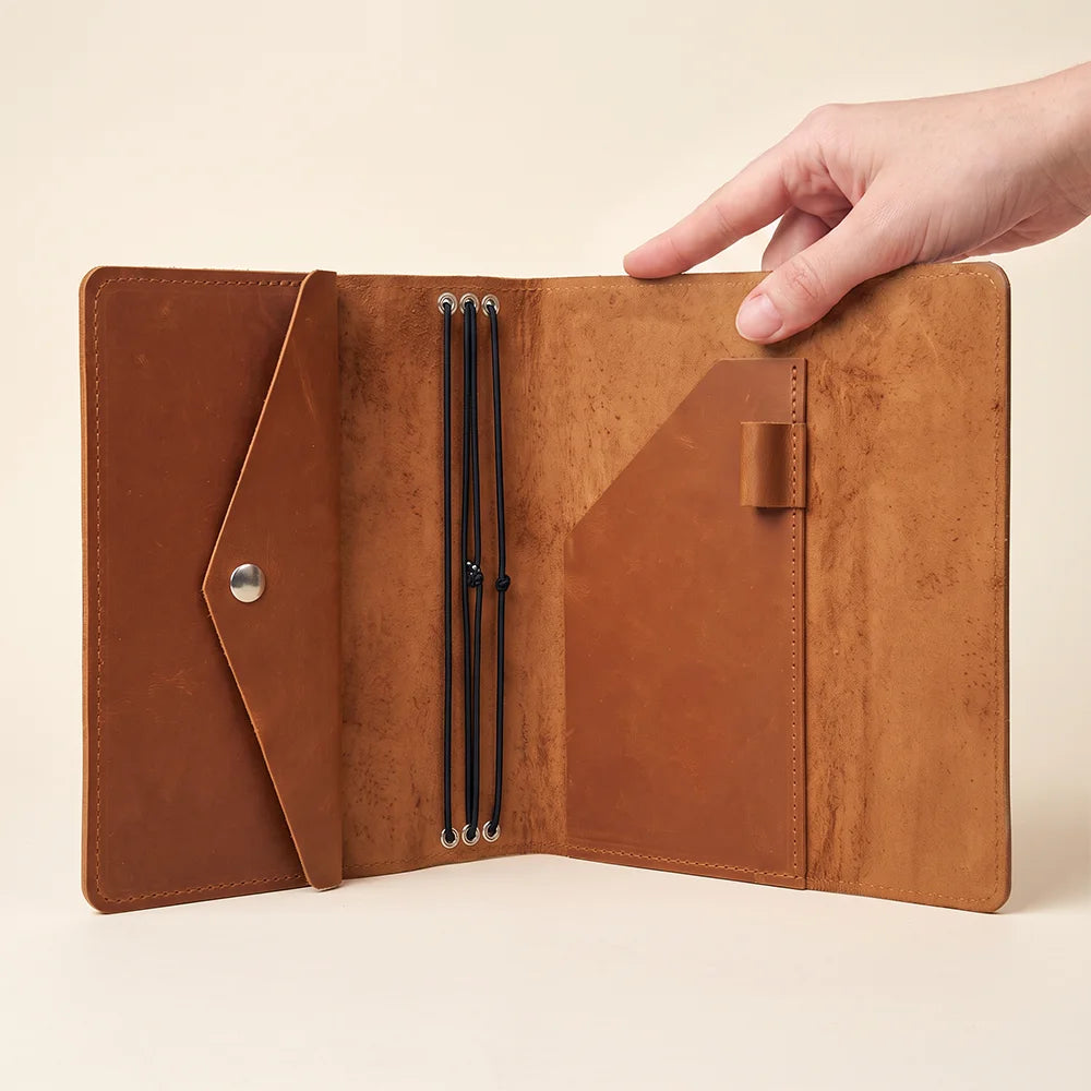 Full grain leather journal organizer with secure notebook retention and interior utility pockets.