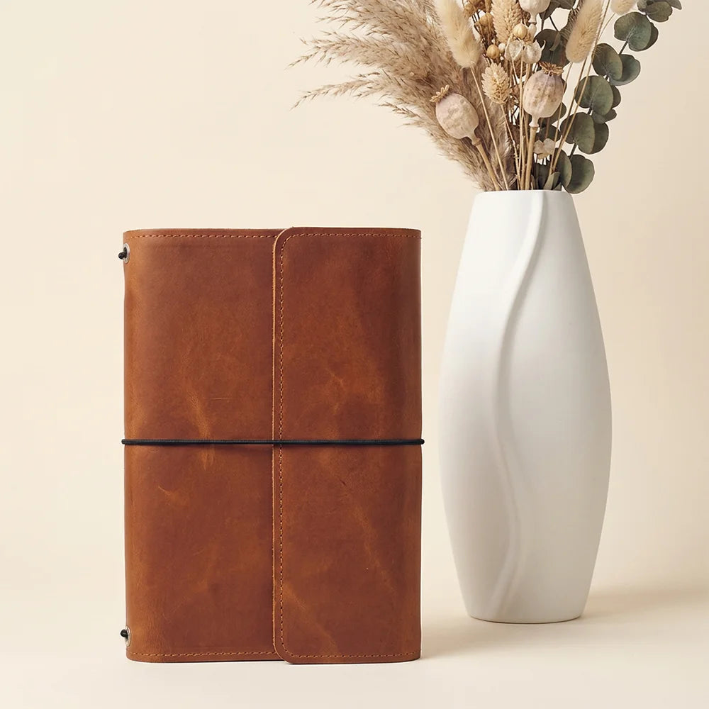 Genuine leather journal sleeve featuring functional storage areas and secure writing accessory placement.