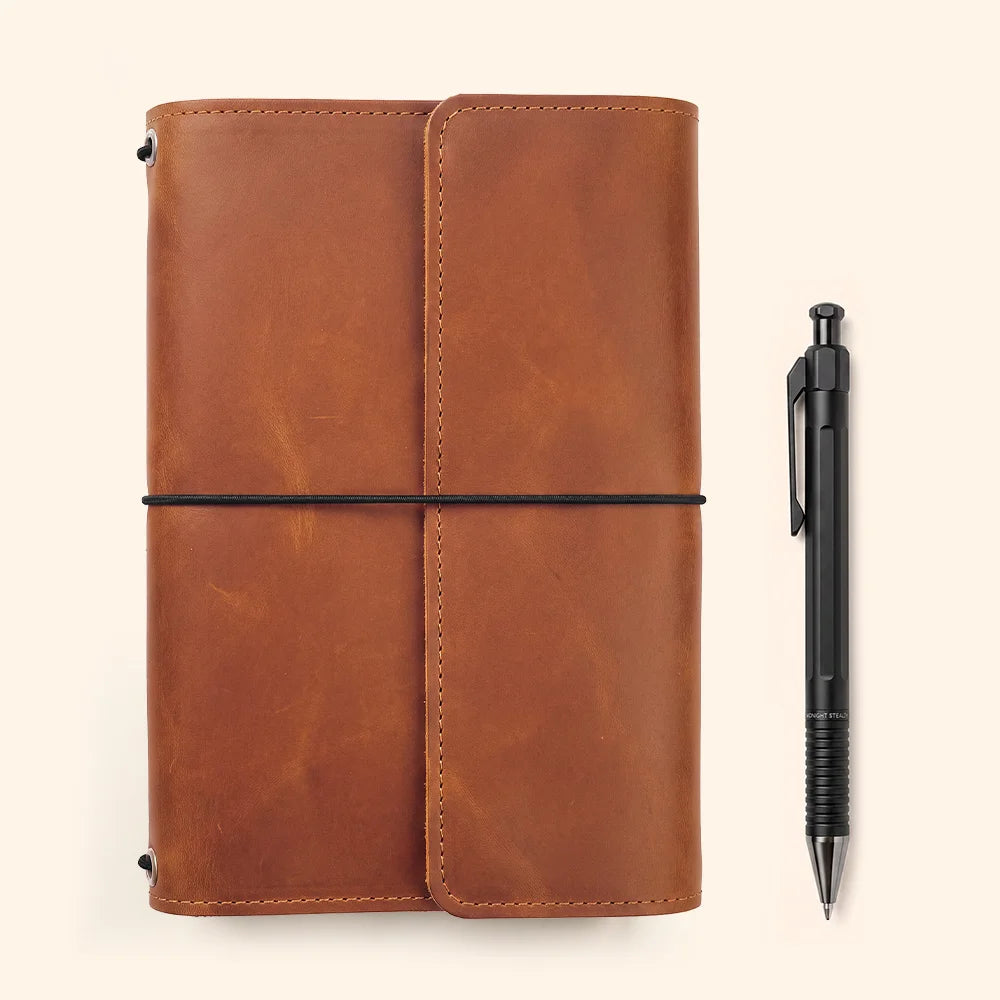 Natural leather planner cover displaying carefully stitched compartments and convenient pen storage inside.