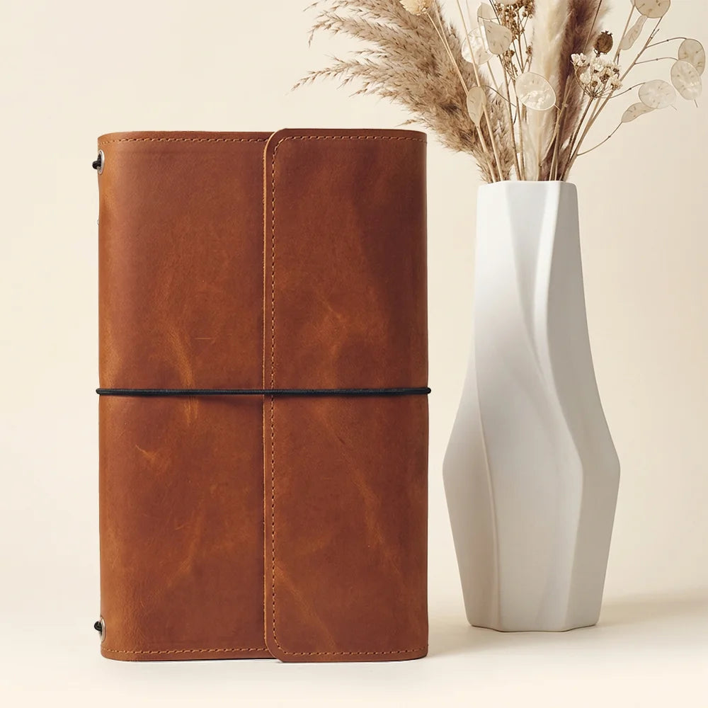 Handmade leather notebook holder displaying spacious compartments and a secure writing tool loop.