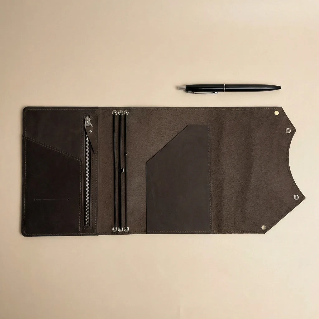 Brown leather journal cover with zipper pocket and pen on a beige background
